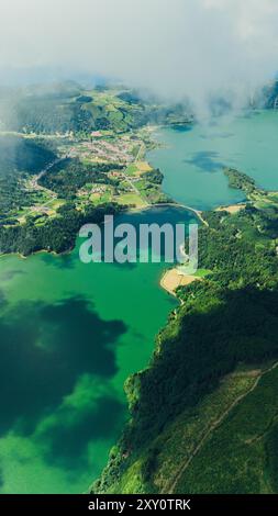 Eine fesselnde Luftaufnahme von grünen Landschaften und azurblauem Wasser zeigt die natürliche Schönheit des Azoren-Nebels und Wolken ziehen sanft über die Ruhe Stockfoto