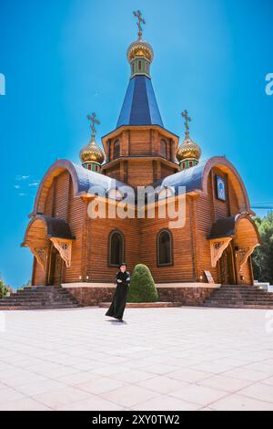 Katholischer Priester, männlich, in traditioneller schwarzer Kleidung gekleidet, stehend vor der reich verzierten orthodoxen katholischen Kirche in Altea, Valencia, Spanien, unter Brig Stockfoto