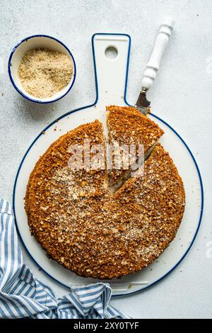 Blick von oben auf einen frisch gebackenen Honigkuchen auf einem weiß-blauen Schneidebrett, mit einer Scheibe sauber geschnitten. Stockfoto