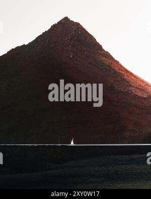 Dieses eindrucksvolle Bild zeigt eine Einzelperson, die vor einem gewaltigen Vulkangipfel auf Lanzarote steht Stockfoto