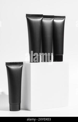 Vier elegante schwarze Kosmetikröhrchen sind vor einem klaren, weißen Hintergrund angeordnet und bieten eine anspruchsvolle und moderne Präsentation. Stockfoto