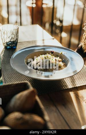 Ein wunderschön angeordneter Teller Gourmet-Pasta, elegant als Teil eines raffinierten Hochzeitsessens serviert. Die Umgebung bietet eine warme Beleuchtung, Stockfoto