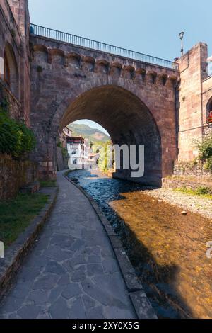 Bogen einer historischen Steinbrücke in Potes. Diese malerische Szene fängt das Wesen des Dorfes ein, eingebettet in die grüne Landschaft von Kantabrien. Stockfoto