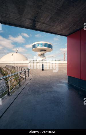 Rückansicht einer nicht erkennbaren Person, die in Richtung des futuristischen Centro Niemeyer in Aviles, Asturien, geht. Das Bild zeigt ein einzigartiges architektonisches Land Stockfoto