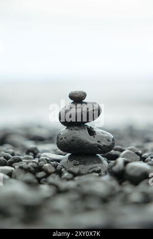 Ein heiterer Stapel von vier glatten Steinen harmoniert perfekt aus, erhebt sich von einem Kieselstrand und steht für Achtsamkeit und Gleichgewicht in einer ruhigen Umgebung Stockfoto