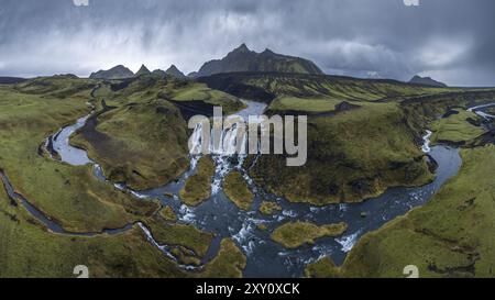 Panoramablick auf Islands Hochland mit bergigen Landschaften, schlängelnden Flüssen und mehreren Wasserfällen inmitten des üppigen Geländes. Stockfoto