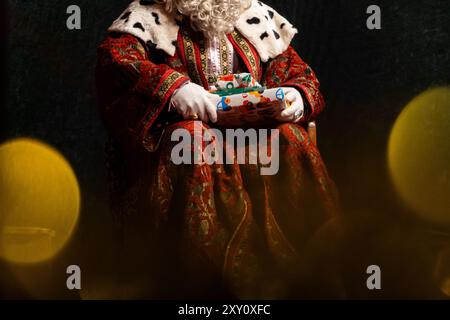 Einer der Weisen, gekleidet in traditionellen, verzierten Gewändern und Pelzen, liefert ein gewickeltes Geschenk, das den Weihnachtsgeist weckt Stockfoto