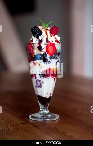"Ein dekadentes Dessert mit einem Glas, das mit Eis gefüllt ist, und verschiedenen frischen Beeren, darunter Erdbeeren, Brombeeren und Himbeeren, Stockfoto