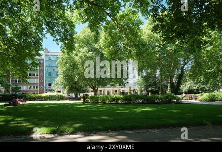 London - 06 14 2022: Kinder spielen und Menschen entspannen sich im Park am St. George's Square Stockfoto