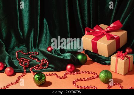 Eine elegante Weihnachtsszene mit Geschenkboxen mit roten Bändern, glänzenden Kugeln und luxuriösem grünem Samtstoff, perfekt für festliche Hintergrundbilder Stockfoto