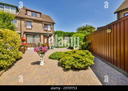 Charmantes zweistöckiges Familienhaus, beleuchtet durch Sonnenlicht, mit einem gepflegten Vorgarten und einer gepflasterten Auffahrt. Stockfoto