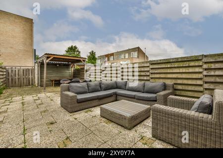 Gemütliches und einladendes Hinterhof-Ambiente mit modernen Rattanmöbeln, einem Holzschuppen und einem robusten Privatzaun. Stockfoto