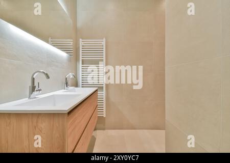 Ein elegantes, modernes Badezimmer mit zwei Waschbecken, beigefarbenen Wänden und warmer Beleuchtung. Stockfoto