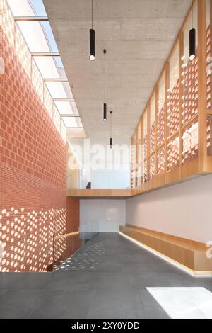 Modernes Innendesign eines Auditoriums mit minimalistischer Architektur und natürlichem Licht, das durch gemusterte Backsteinwände gefiltert wird. Stockfoto