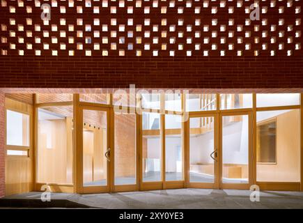 Ein zeitgenössischer Eingang im Auditorium mit einer markanten Ziegeldecke, durch die natürliches Licht gefiltert wird, ergänzt durch Holztüren und ein warmes i Stockfoto