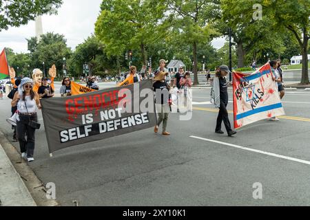 Washington DC, USA - 19.08.2024: Eine Gruppe von Menschen marschiert die Straße hinunter mit Schildern, auf denen steht: "Völkermord ist keine Selbstverteidigung." Stockfoto