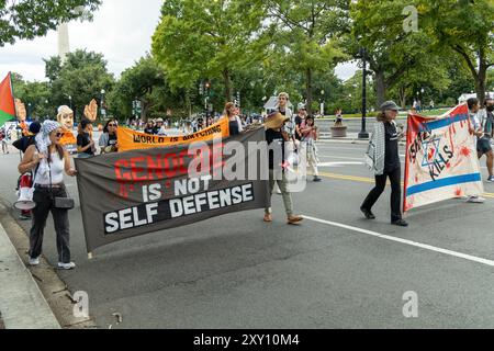 Washington DC, USA - 19.08.2024: Eine Gruppe von Menschen marschiert die Straße hinunter mit Schildern, auf denen steht: "Völkermord ist keine Selbstverteidigung." Stockfoto