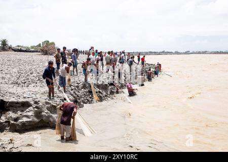 Feni, Chittagong, Bangladesch. August 2024. 27. August 2024, Feni, Chittagong, Bangladesch: Fischer und gewöhnliche Menschen fischen mit handgefertigten Netzen am Ufer des Feni River, wobei sie den starken Fluss von Hochwasser entlang des Muhuri-Projekts in Sonagazi Upazila, Bezirk Feni, Division Chittagong, Bangladesch ignorieren. (Kreditbild: © Muhammad Amdad Hossain/ZUMA Press Wire) NUR REDAKTIONELLE VERWENDUNG! Nicht für kommerzielle ZWECKE! Stockfoto