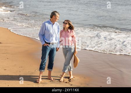 Ein Paar genießt einen romantischen Spaziergang am Strand bei Sonnenuntergang im Sommer Stockfoto