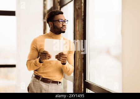 Träumender Afro Manager mit wegschauendem Tablet Stockfoto