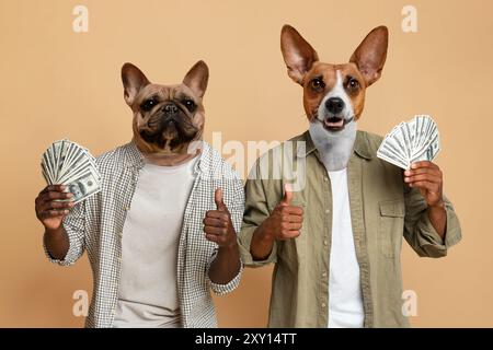 Zwei Hunde, die Hemden tragen, Geld halten und Daumen hochgeben Stockfoto