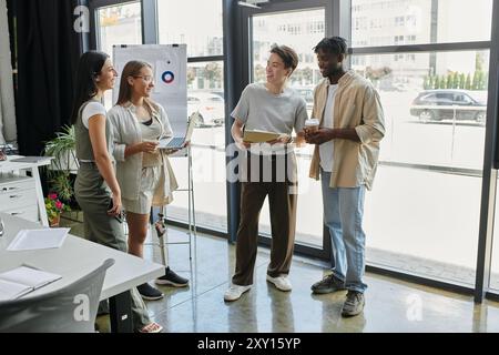 Ein Team von vier jungen Fachleuten arbeitet in einem hellen, modernen Bürobereich zusammen. Stockfoto