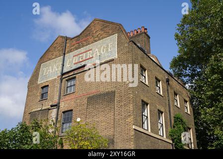 Die Seite eines Wohnhauses in Borough mit einem alten Ladenwerbung-Schild an der Wand. London - 26. August 2024 Stockfoto