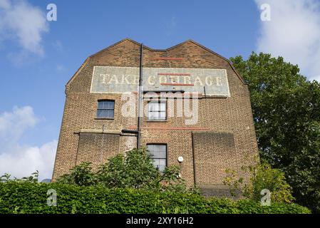 Die Seite eines Wohnhauses in Borough mit einem alten Ladenwerbung-Schild an der Wand. London - 26. August 2024 Stockfoto