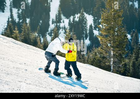 Goderdzi, Georgia - 13. januar 2023: Männliche Hipster-Instruktoren zeigen, wie man Snowboarder Balance hält Anfänger Snowboarder bergab auf weiß Stockfoto