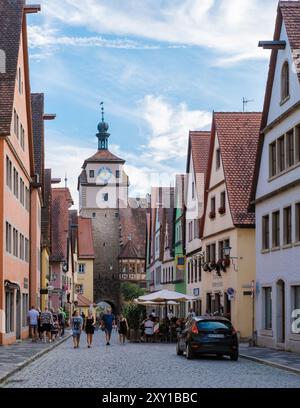 Rothenburg ob der Tauber, Deutschland 25. August 2024, Besucher schlendern durch die kopfsteingepflasterten Straßen Rothenburg ob der Taubers und bewundern historische Fachwerkhäuser und leuchtende Farben unter einem hellblauen Himmel Stockfoto