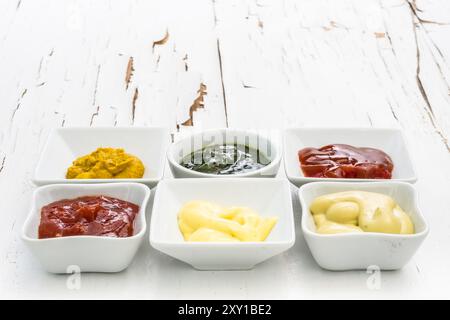 Klassisches Set Saucen in quadratischen weißen Saugern auf Oberfläche mit gerissener Farbe Stockfoto