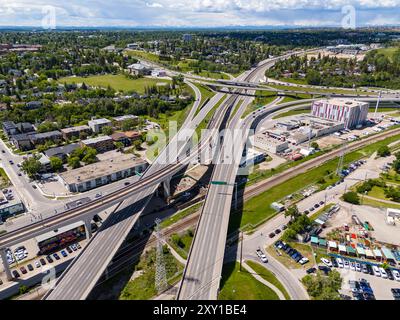 Calgary Alberta Canada, 20. Juni 2024: Blick von oben auf Überführungen und Durchgangsstraßen mit Blick auf die Straßen der Stadt und die fernen Berge. Stockfoto