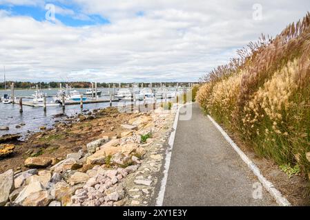 Verlassener Fußweg am Hafen an einem bewölkten Herbsttag. Boote, die an den Anlegestellen liegen, sind im Hintergrund Stockfoto