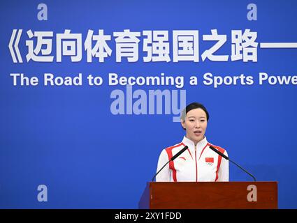 (240827) -- PEKING, 27. August 2024 (Xinhua) -- Feng Yu, Teamleiter des chinesischen künstlerischen Schwimmteams und Vertreter der Goldmedaillengewinner bei den Olympischen Spielen 2024 in Paris, spricht während einer Eröffnungszeremonie in Peking, der Hauptstadt Chinas, am 27. August 2024. Ein Think Tank-Bericht mit dem Titel „The Road to Being a Sports Powerhouse – the Value and Inspiration of Xi Jinping's Important Discourses on Sports“ wurde hier am Dienstag veröffentlicht. Der Bericht wurde vom Xinhua Institute, einem High-End-Think Tank der Xinhua Nachrichtenagentur, verfasst und ist in vier Abschnitte gegliedert. Es erklärt ausführlich die Kernkonzepte von Xis i Stockfoto