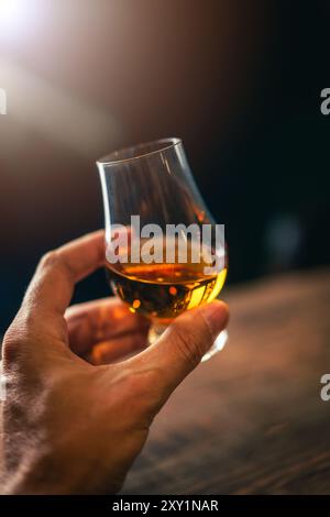 Farb-Nahaufnahme einer Hand, die ein einzelnes Glencairn Whiskyglas hält. Stockfoto