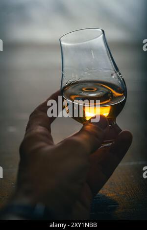 Farb-Nahaufnahme einer Hand, die ein einzelnes Glencairn Whiskyglas hält. Stockfoto