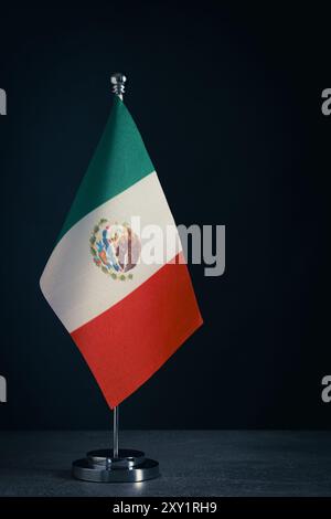 Flagge von Mexiko auf Metall Tischhalter dunklem Hintergrund. Die Farben sind grün, weiß und rot mit den Wappen in der Mitte Stockfoto