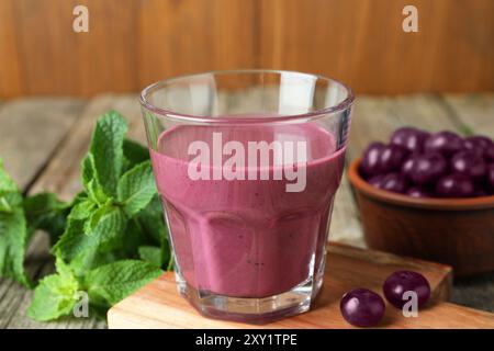 Leckerer frischer Acai-Saft im Glas mit Beeren und Minze auf dem Tisch, Nahaufnahme Stockfoto