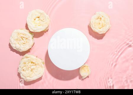 Schöne Rosenblüten und rundes Podium im Wasser auf rosa Hintergrund, flach gelegen Stockfoto