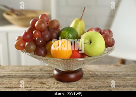 Glasvase mit verschiedenen frischen Früchten auf Holztisch Stockfoto