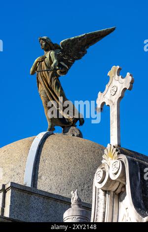 Ein Kreuz und eine Engelsstatue auf einem aufwendigen Grab oder Mausoleum auf dem Recoleta Friedhof in Buenos Aires, Argentinien. Stockfoto