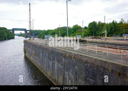 Manchester Ship Canal. Leere Kanalschleuse Irlam mit Industriemaschinen und Grün im Hintergrund an einem bewölkten Tag. Stockfoto