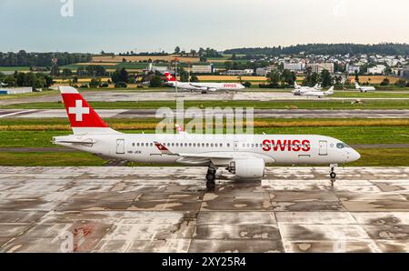 Ein Airbus A220-371 von Swiss International Airlines rollt, nach einem Gewitter, auf dem Flughafen Zürich zur Startbahn. Registrierung HB-JCK. (Zürich, Stockfoto