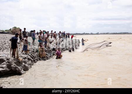 Feni, Chittagong, Bangladesch. August 2024. 27. August 2024, Feni, Chittagong, Bangladesch: Fischer und gewöhnliche Menschen fischen mit handgefertigten Netzen am Ufer des Feni River, wobei sie den starken Fluss von Hochwasser entlang des Muhuri-Projekts in Sonagazi Upazila, Bezirk Feni, Division Chittagong, Bangladesch ignorieren. (Kreditbild: © Muhammad Amdad Hossain/ZUMA Press Wire) NUR REDAKTIONELLE VERWENDUNG! Nicht für kommerzielle ZWECKE! Stockfoto