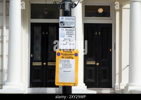 Hinweis zur Parksperre in Wohngebieten für Notting Hill Carnival Grand Parade 2024. Kensington Park Gardens Lampensäule mit elektrischer Ladestation Stockfoto