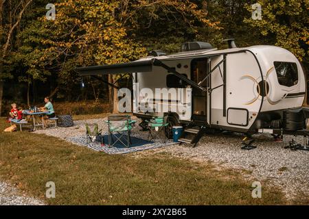 Familie genießt Urlaub auf dem Campingplatz Picknicktisch mit Trailer in der Natur Stockfoto