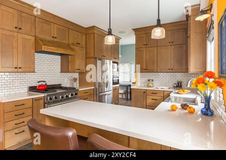 Anderer Winkel der renovierten Küche in einem älteren Haus mit Holzschränken und hell orange Wand Stockfoto