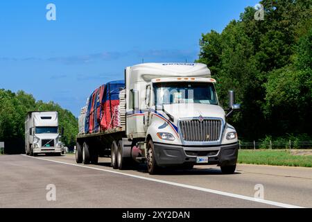 Knoxville, Tennessee, USA – 20. August 2024: Horizontale Aufnahme eines schweren beladenen Flachbetts, das den Verkehr entlang einer Tennessee interstate führt. Hea Stockfoto