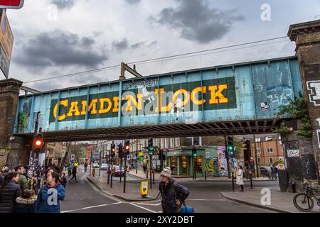 Menschen und Touristen, die unter der legendären Eisenbahnbrücke Camden Lock auf der Camden High Street spazieren, die den Regent's Canal in Camden Town überquert Stockfoto