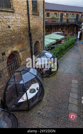 Menschen und Freunde trinken Kaffee und Bier in Speisekapseln in der historischen Brick Gasse des Londoner Camden Market. Stockfoto